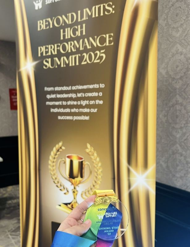 Angelica holding her Concentrix Creators Support Shining Star Award Q2 medal in front of the Beyond Limits: High Performance Summit 2025 banner
